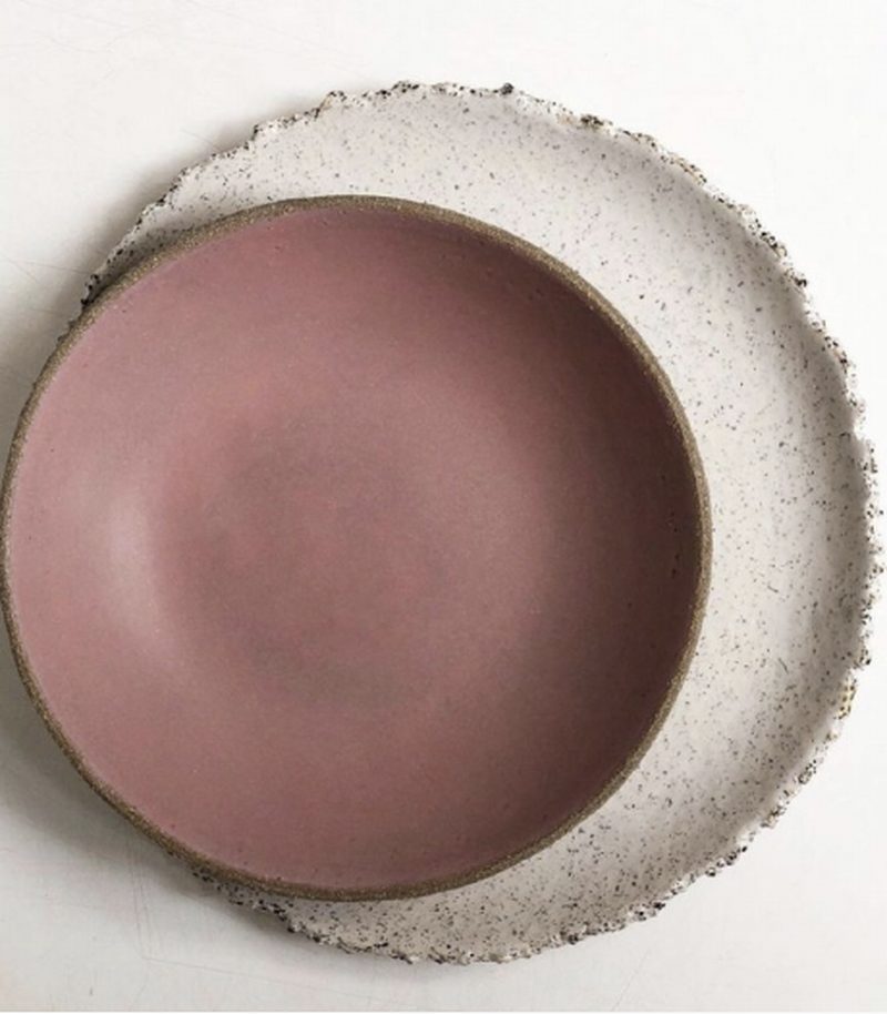 Cuenco de cerámica rosa sobre plato de piedra